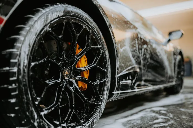 Car wheel covered in soap suds during a wash