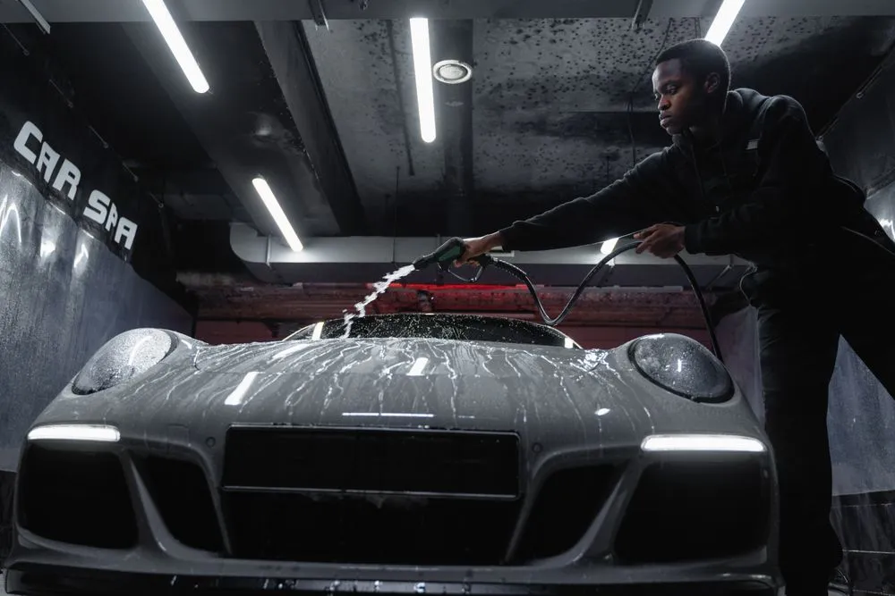Detailer washing a white sports car